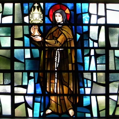 St. Clare of Assisi holds the Blessed Sacrament. Tradition holds that Clare met those who were about to plunder the city; as the enemy gazed upon the Eucharist, they retreated.